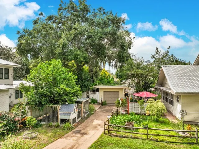 a backyard of a house with table and chairs plants and large trees