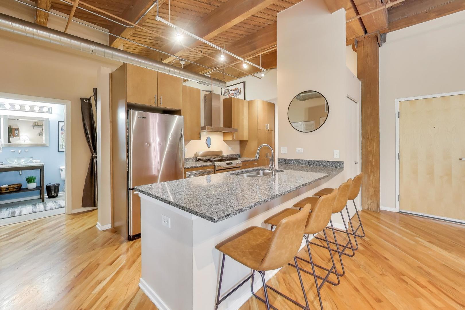 1040 West Adams Street, Unit 370 Chicago, IL 60607 - Photo 5 of 27 a kitchen with stainless steel appliances granite countertop a sink a refrigerator counter space and wooden floor