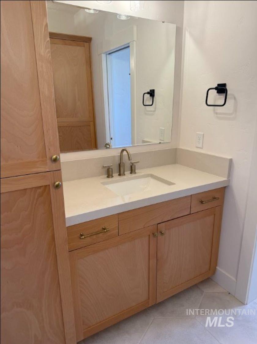 755 West Wrangler Street Meridian, ID 83646 - Photo 23 of 35 Bathroom vanity featuring a light wood-finish cabinetry, solid surface countertop, undermount sink, and brushed nickel faucet
