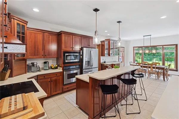 a kitchen with stainless steel appliances granite countertop a stove top oven a refrigerator a sink and chairs