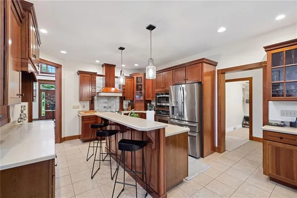 a kitchen with stainless steel appliances kitchen island granite countertop a refrigerator a stove top oven a sink dishwasher and white cabinets with wooden floor