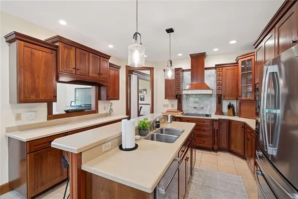 a kitchen with stainless steel appliances granite countertop a refrigerator a sink dishwasher a stove and a dining table with wooden floor