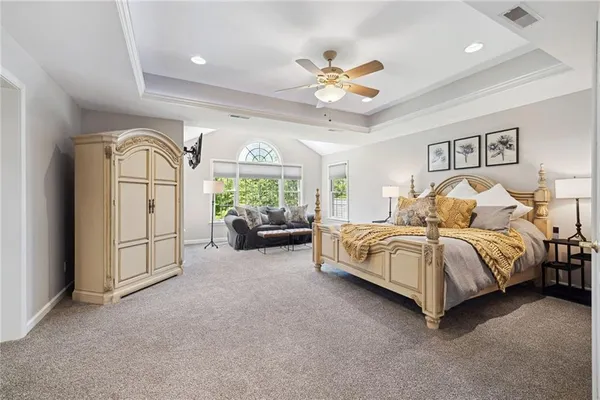 a spacious bedroom with a bed painting on wall and a large window