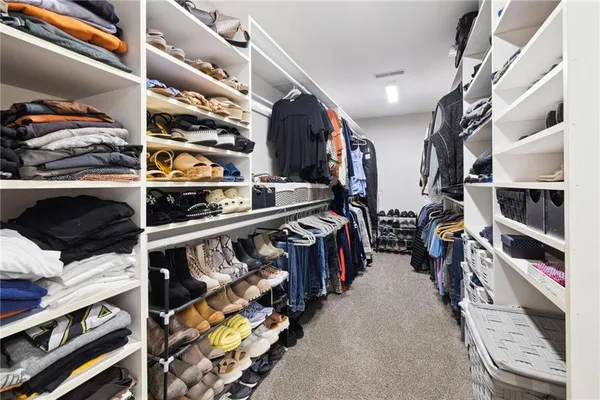 a view of walk in closet with clothes and shoes
