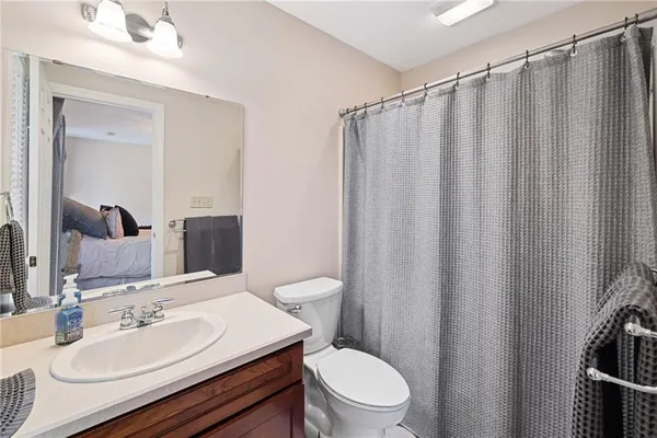 a bathroom with a sink a toilet a mirror and shower curtain