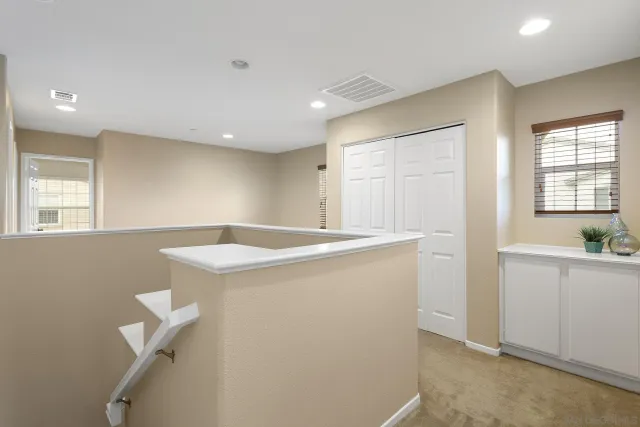 an empty room with chandelier fan and windows
