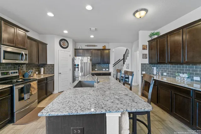 a kitchen with stainless steel appliances granite countertop a sink stove and refrigerator