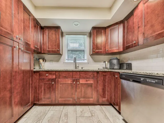 a kitchen with granite countertop wooden cabinets a sink and dishwasher