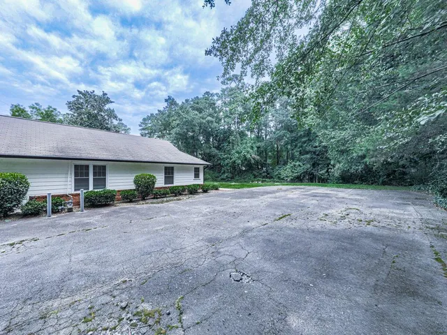a view of a house with a yard and large trees