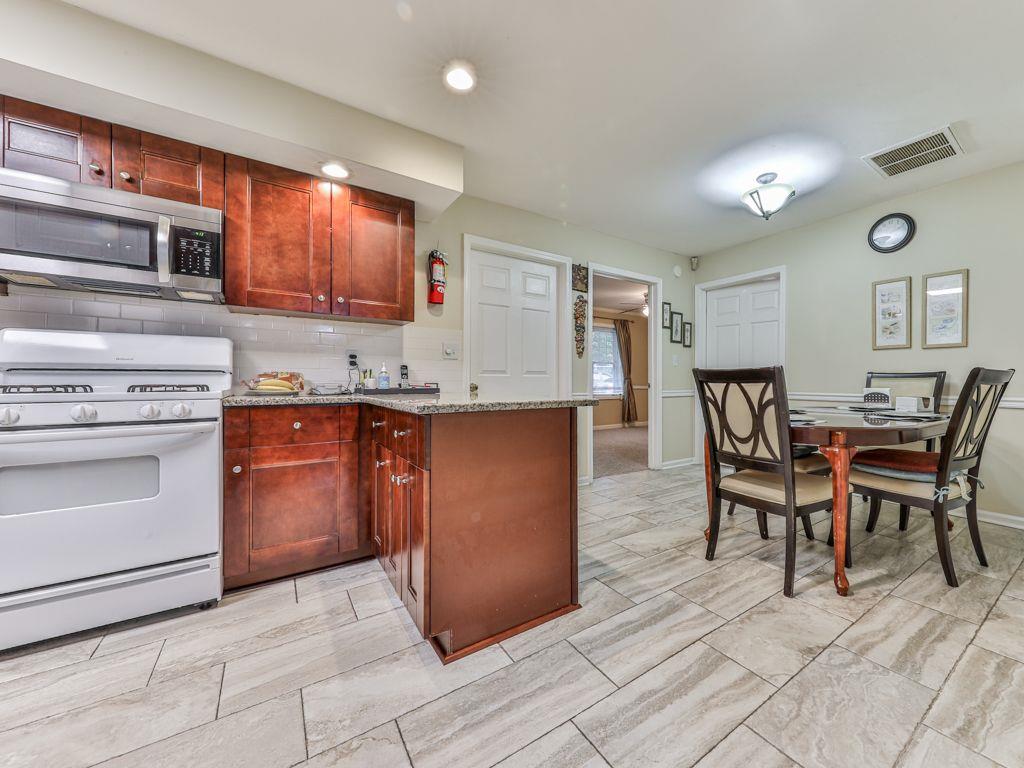3605 Shallowford Road Marietta, GA 30062 - Photo 10 of 42 a kitchen with kitchen island a stove a table and chairs in it
