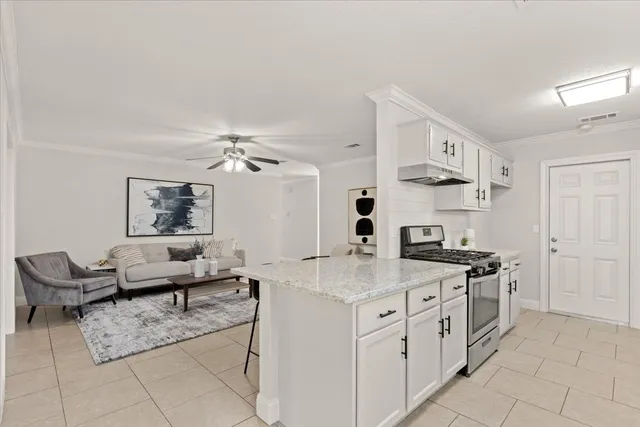 a living room with furniture a table and kitchen view