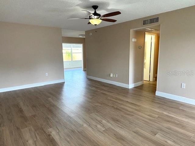 1005 Rickenbacker Drive Sun City Center, FL 33573 - Photo 4 of 57 an empty room with wooden floor chandelier fan and windows