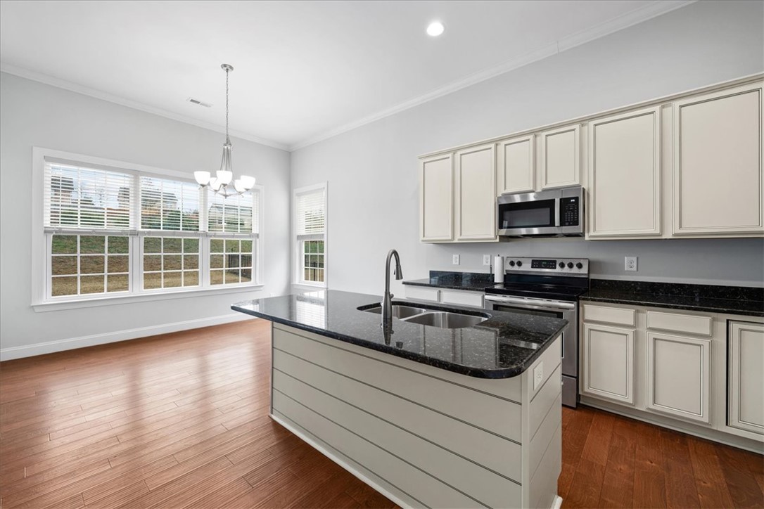 102 Ripplestone Way Anderson, SC 29621 - Photo 10 of 39 A well-lit culinary space features rich hardwood flooring and sleek, dark granite countertops.