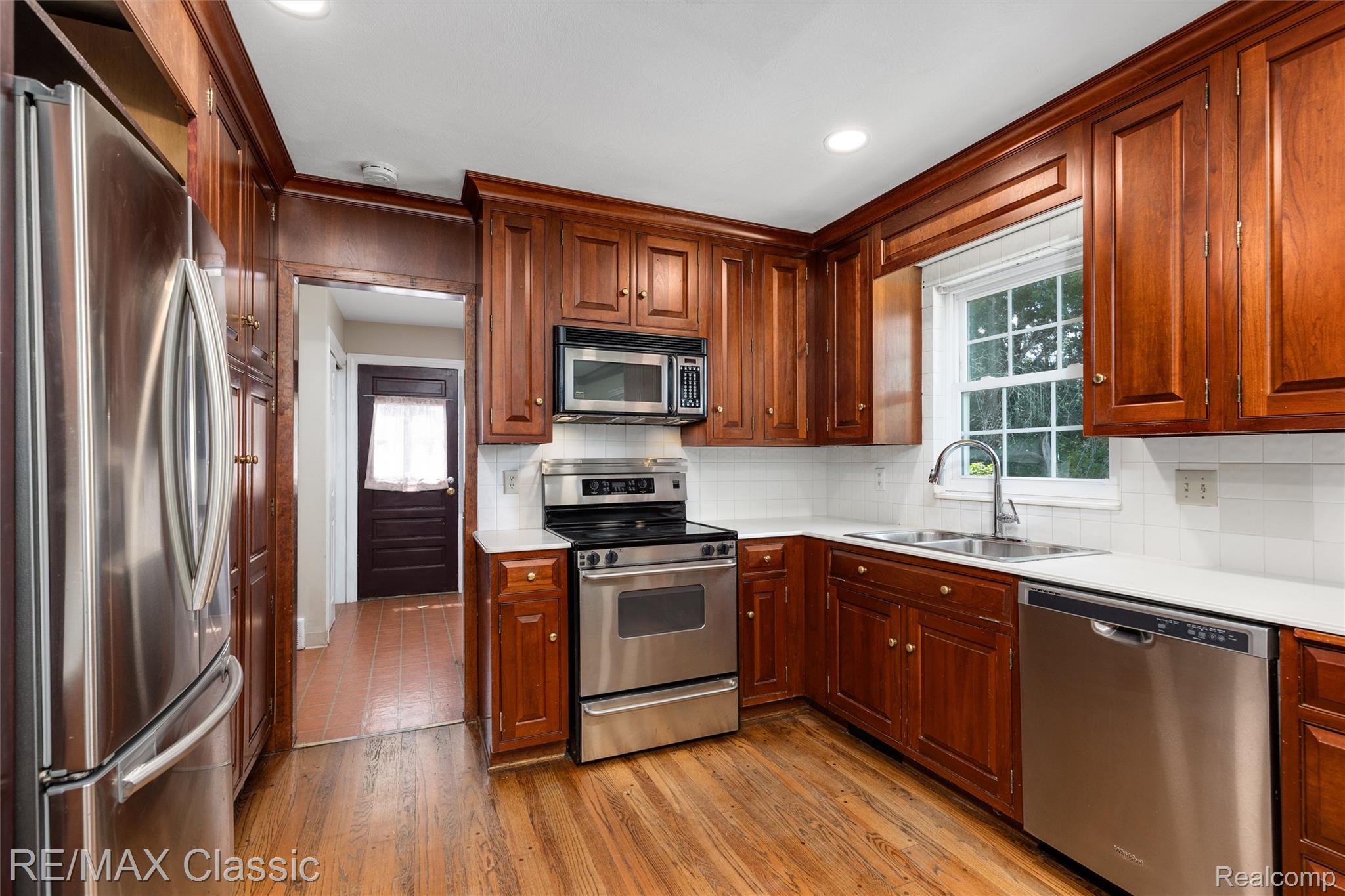4268 Covered Bridge Road Bloomfield Hills, MI 48302 - Photo 2 of 35 Kitchen featuring wood cabinetry, stainless steel appliances, white countertops, white subway tile backsplash, and wood-finish flooring