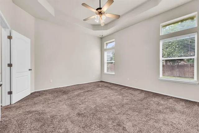 an empty room with windows and fan