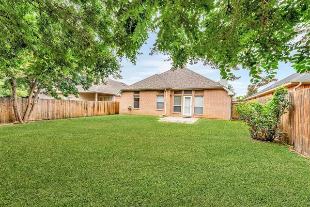 a view of a yard in front of a house with plants and large tree