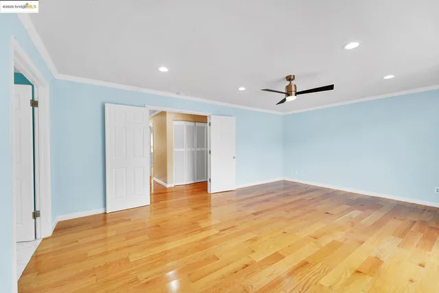 a view of an empty room with window and wooden floor