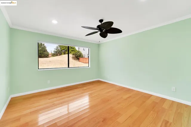 a view of a room with a large window a ceiling fan and wooden floor