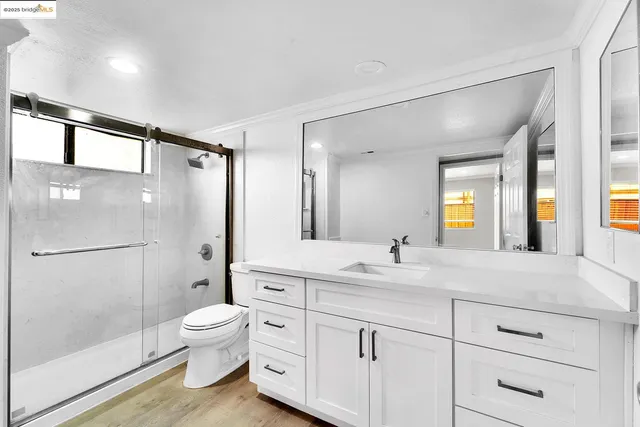 a bathroom with a double vanity sink toilet mirror and shower