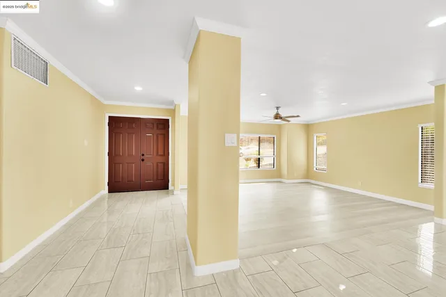 a view of an empty room with kitchen and a window