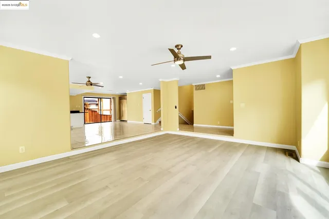 a view of empty room with wooden floor and ceiling fan