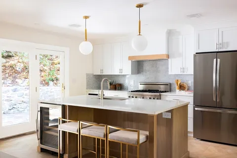 a kitchen with kitchen island a stove a sink a refrigerator and chairs
