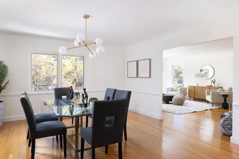 a dining room with wooden floor a chandelier a glass table and chairs