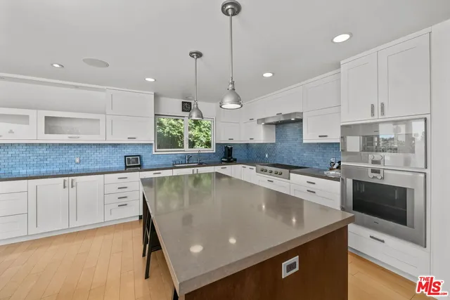 a kitchen with stainless steel appliances granite countertop a sink a stove a refrigerator and white cabinets