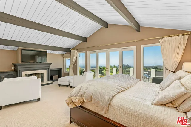 a large bedroom with a large bed a flat tv screen and a fireplace