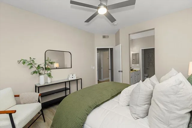 a bedroom with a bed chandelier painting on the wall and a potted plant