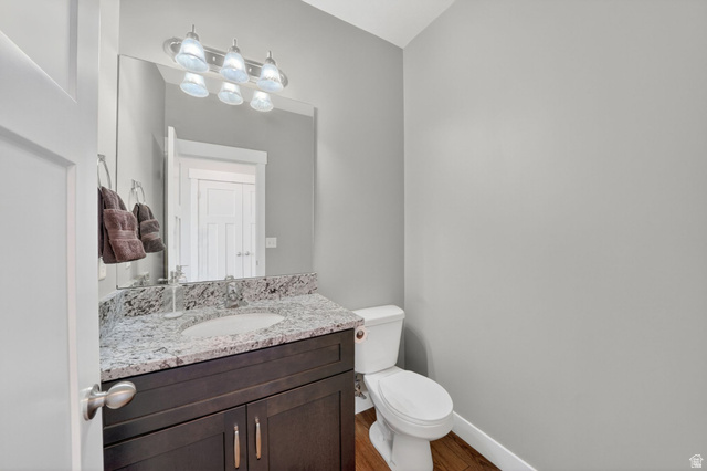 7872 Farm House Lane Midvale, UT 84047 - Photo 15 of 39 Bathroom featuring a vanity with a granite-style countertop, undermount sink, dark wood-finish cabinetry, and a wall-mounted mirror with an overhead light fixture