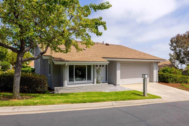 a view of a house with a yard and large tree