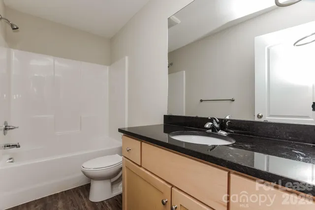 a bathroom with a granite countertop sink a toilet and bathtub