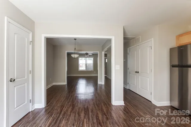 a view of a hallway with wooden floor and a living room