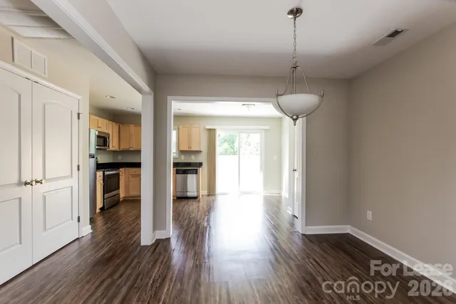 a view of a hallway with wooden floor and a kitchen