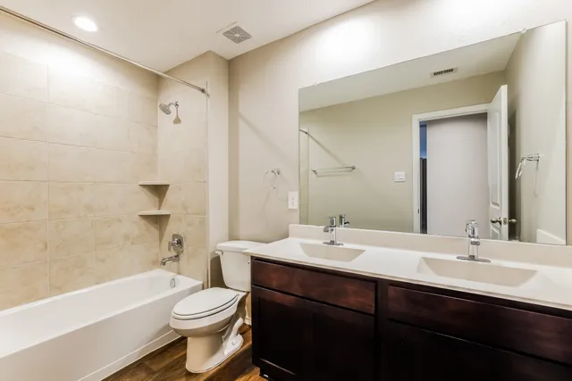 a bathroom with a sink a toilet a mirror a bathtub and shower