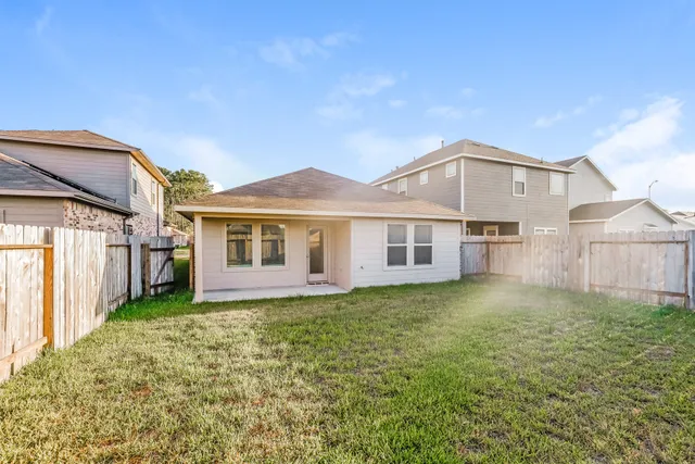 a view of a yard in front of a house with plants and wooden fence