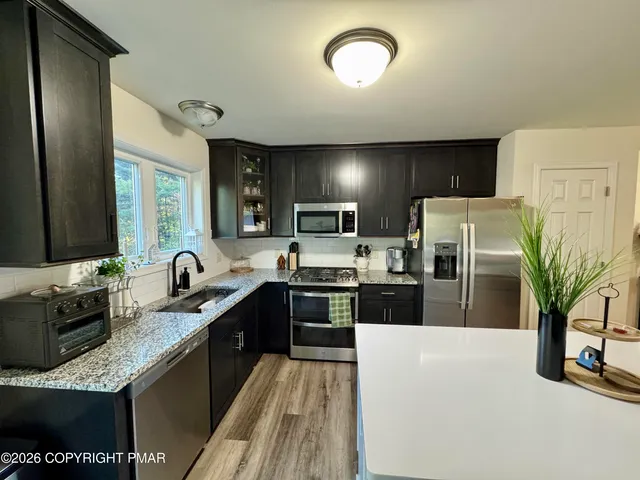 a kitchen with stainless steel appliances granite countertop a sink a stove top oven a refrigerator with wooden floors