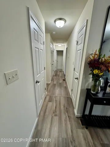 a view of a hallway to a livingroom with wooden floor and furniture