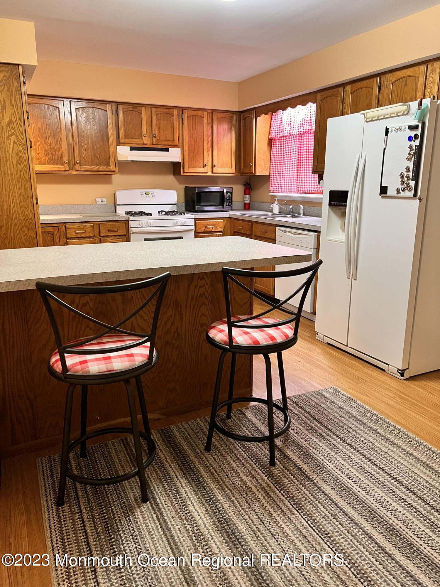 515 Eastern Boulevard Bayville, NJ 08721 - Photo 7 of 38 a kitchen with a refrigerator a stove and a dining table with wooden floor