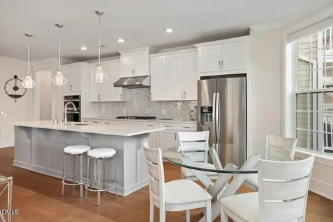 a kitchen with kitchen island granite countertop a table chairs refrigerator a sink and a stove