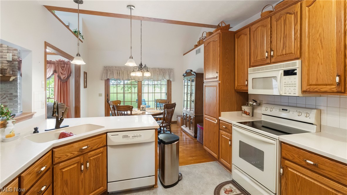 2880 Durst Clagg Road Warren, OH 44481 - Photo 15 of 25 Kitchen with a notable chandelier, hanging light fixtures, light wood-type flooring, white appliances, and backsplash