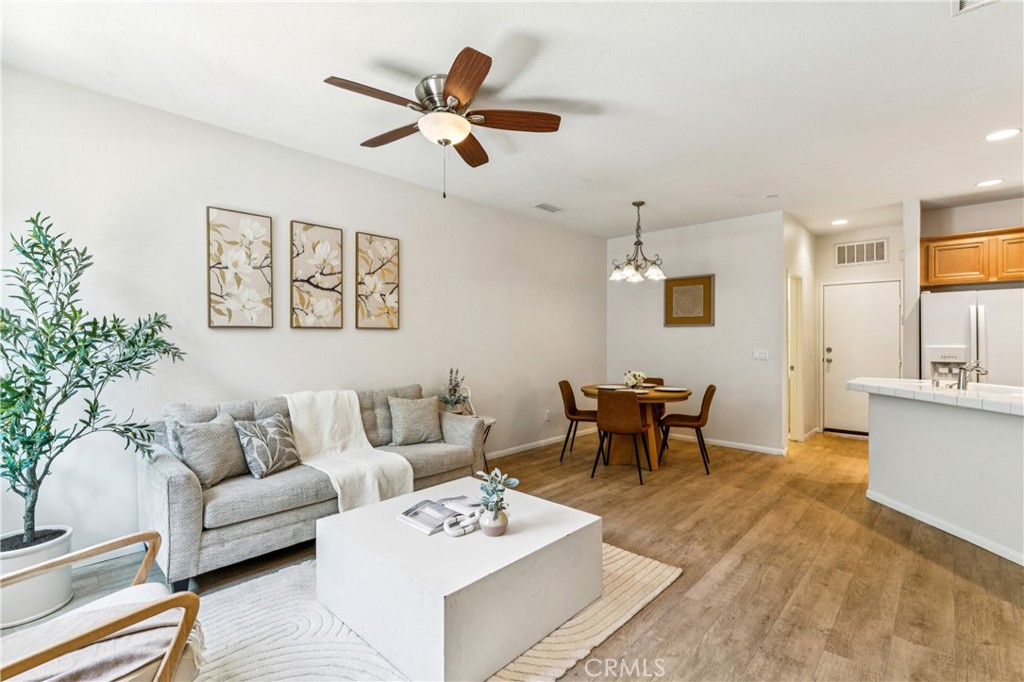 8048 Tulsa Place, Unit 105 Rancho Cucamonga, CA 91730 - Photo 8 of 45 a living room with furniture a dining table and paintings on the wall with wooden floor