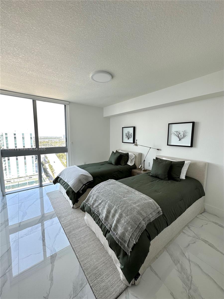 330 Sunny Isles Boulevard, Unit 52002 Sunny Isles Beach, FL 33160 - Photo 16 of 56 a bedroom with two beds and a large window