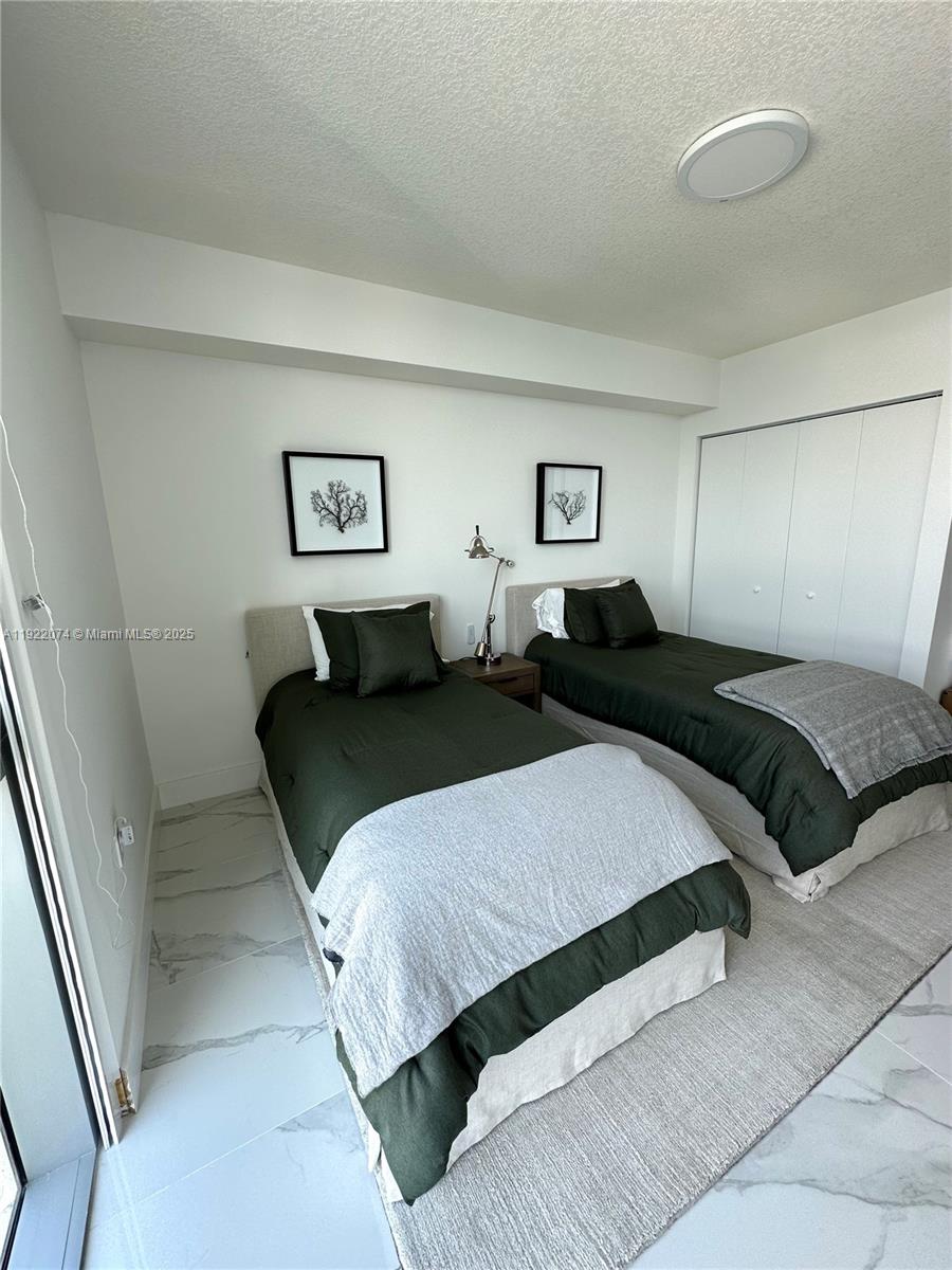 330 Sunny Isles Boulevard, Unit 52002 Sunny Isles Beach, FL 33160 - Photo 17 of 56 a bedroom with a bed and a night stand