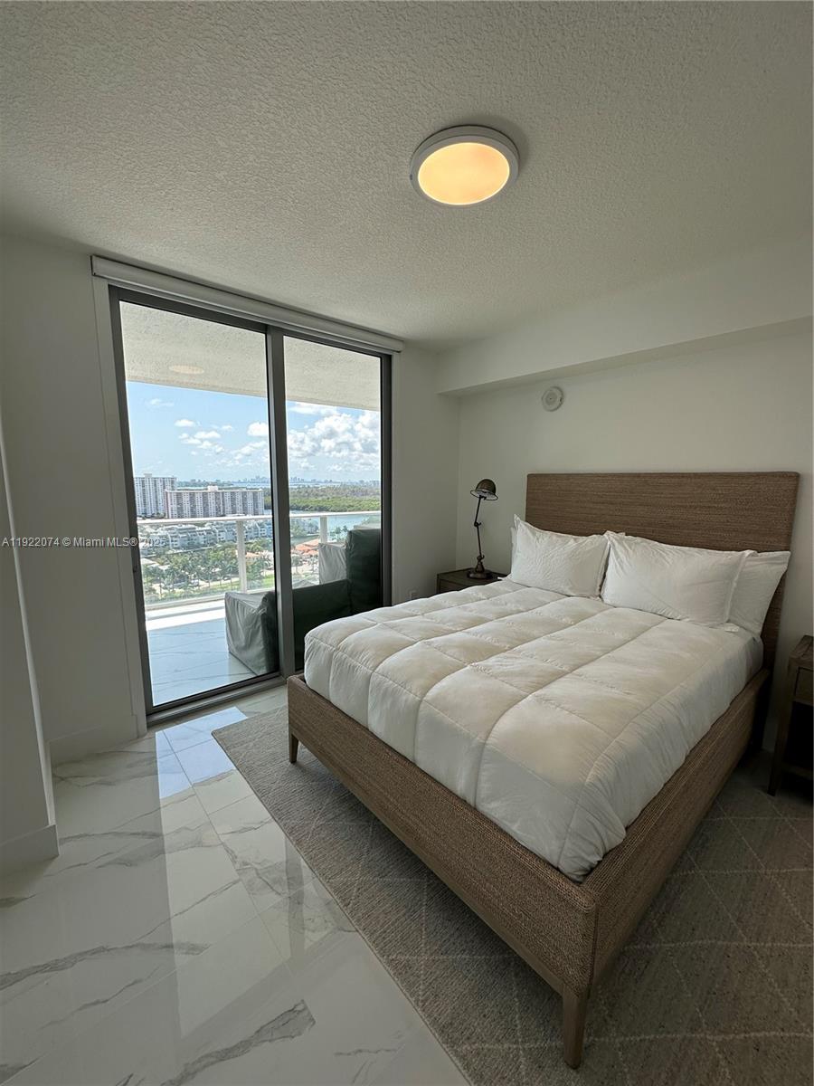 330 Sunny Isles Boulevard, Unit 52002 Sunny Isles Beach, FL 33160 - Photo 41 of 56 a bedroom with a bed and glass window