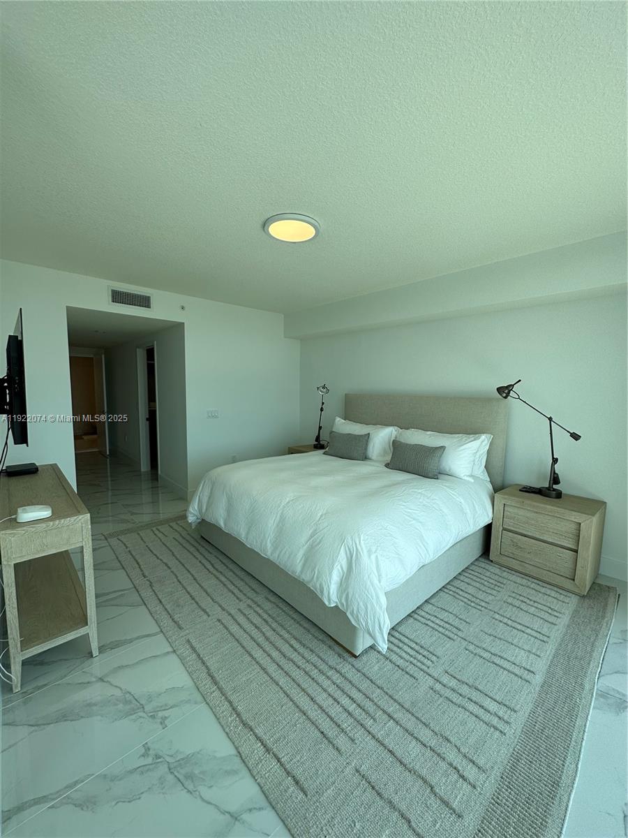 330 Sunny Isles Boulevard, Unit 52002 Sunny Isles Beach, FL 33160 - Photo 46 of 56 a bedroom with a bed and a chandelier