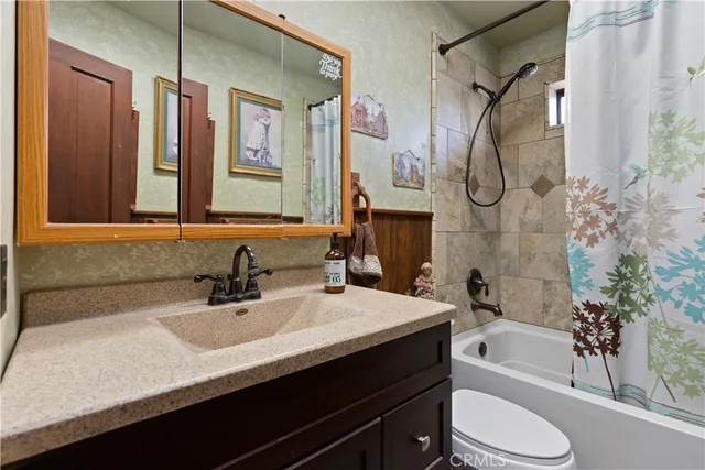 a bathroom with a granite countertop sink a toilet a mirror and shower