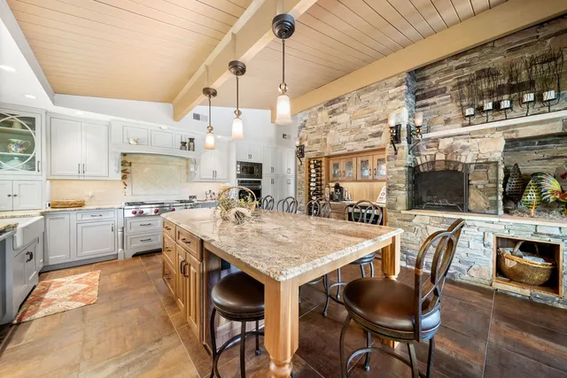 a kitchen with stainless steel appliances granite countertop a table chairs and a refrigerator