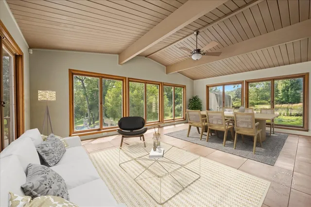 a living room with furniture a large window and dining table